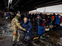 A Ukrainian serviceman helps evacuees gathered under a destroyed bridge, as they flee the city of Irpin, northwest of Kyiv, on March 7.