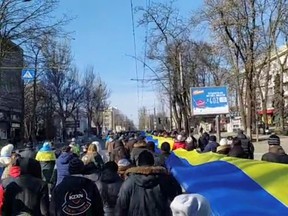 Live-streamed footage shows people carrying a banner in the colours of the Ukrainian flag as they protest amid Russia's invasion of Ukraine, in Kherson, Ukraine, March 13, 2022 in this still image from a social media video obtained by Reuters.