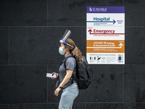 A health care worker wearing a mask and sheild walks past St. Mike's Hospital in Toronto during the Covid 19 pandemic, Friday January 15, 2021.