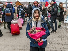 A young Ukrainian refugee carries her beloved dog in her arms as she waits at the Ukrainian Polish border in Medyka, Poland. Forced to flee her home with only what she could carry, she chose her dog.