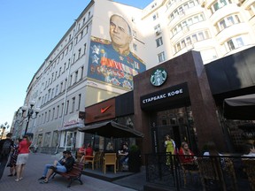 A wall mural, depicting Russian General Georgy Zhukov, a World War II Soviet hero, sits on a building above a Nike Inc. sportswear store and a Starbucks Corp. coffee shop on Arbat street in Moscow, Russia, on Monday, June 8, 2015.