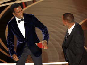 Chris Rock reacts after being hit by Will Smith (R) as Rock spoke on stage during the 94th Academy Awards in Hollywood, California, March 27, 2022.