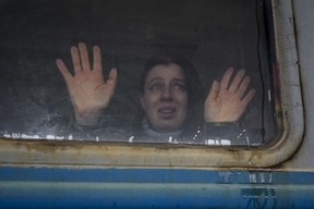 A woman looks toward relatives and presses her palms against a window of a Lviv-bound train, on the platform in Kyiv, Ukraine on March 3, 2022.