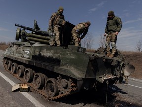 Ukrainian soldiers stand on top of a Russian artillery vehicle they captured during fighting outside Kharkiv, as Russia's attack on Ukraine continues, Ukraine, March 29, 2022.