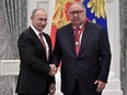 Russian President Vladimir Putin, left, shakes hands with Russian businessman and founder of USM Holdings Alisher Usmanov during an awards ceremony at the Kremlin in Moscow in 2018.