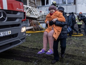 A man carries an elderly resident to safety after she was rescued by firefighters from a high floor at a residential apartment building after it was hit by a Russian attack in the early hours of the morning in the Sviatoshynskyi District on March 15, 2022 in Kyiv, Ukraine.