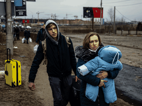 Eine Frau trägt ihr Kind, als sie am 7. März 2022 aus der Stadt Irpin nordwestlich von Kiew fliehen.