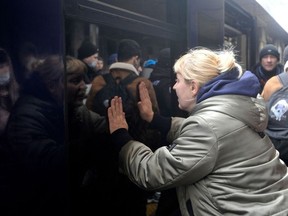 A woman says goodbye as a train with evacuees is about to leave Kyiv's railway station on March 2, 2022. (Photo by Sergei CHUZAVKOV / AFP)