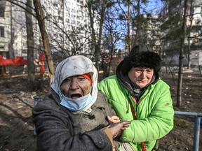 A woman is evacuated from a burning apartment building in Kyiv on March 15, 2022, after strikes on residential areas killed at least two people, Ukraine emergency services said as Russian troops intensified their attacks on the Ukrainian capital.