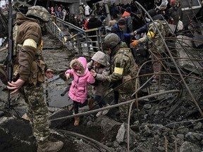 People cross a destroyed bridge as they evacuate the city of Irpin, northwest of Kyiv, during heavy shelling and bombing on March 5.