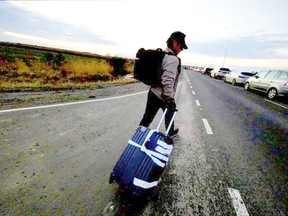 Sean Pean shared a photograph of himself pulling a suitcase along a road and wrote: 'Myself and two colleagues walked miles to the Polish border after abandoning our car on the side of the road'.