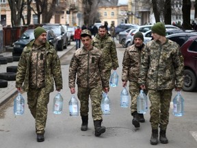 Ukrainian soldiers carry water supplies near a military base in Lviv on March 2, 2022.