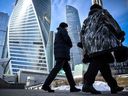 Frauen gehen vor dem Moskauer International Business Center (Moskva City) Komplex in Moskau.  Unternehmen und Haushalte stehen vor einem zweistelligen Wirtschaftseinbruch und einer Inflation, die sich auf 20 Prozent beschleunigt. 