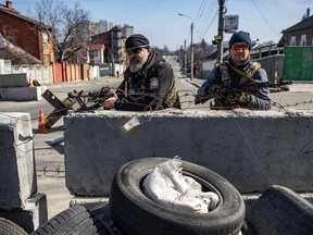 Ukrainian volunteer fighters take position at a checkpoint in their district in Kyiv on March 20, 2022, as Russian forces try to encircle the Ukranian capital.