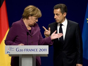 German Chancellor Angela Merkel (L) and French President Nicolas Sarkozy talk as they arrive for a press conference after a meeting with Greek Prime Minister George Papandreou and EU and IMF representatives at the G20 summit on November 2, 2011 in Cannes, France.