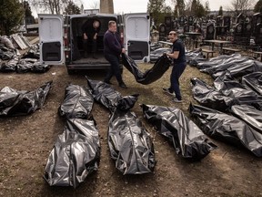 Cemetery workers unload bodies of civilians killed in and around Bucha before they are transported to the morgue at a cemetery, on April 07, 2022.