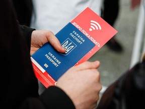 Ukrainian refugee holds a passport and a flyer for mobile phone SIM cards in his hand at the main railway station (Hauptbahnhof) in Dresden, eastern Germany, on March 22, 2022.