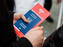 Ukrainischer Flüchtling hält am 22.03.2022 am Hauptbahnhof in Dresden einen Reisepass und einen Flyer für Handy-SIM-Karten in der Hand.