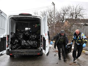 Communal workers carry a body of a civilian man killed by Russian troops shelling in town of Bucha, not far from the Ukrainian capital of Kyiv on April 3, 2022.