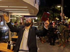 Ein ultra-orthodoxer Jude reagiert, während er einen Band des Buches der Psalmen in der Hand hält, während sich Sicherheitskräfte am 7.