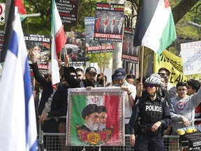 Participants wave Iranian flags and display a portrait of the Ayatollahs at the 2019 Al-Quds Day march in downtown Toronto.