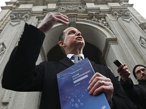Quebec Finance Minister Eric Girard holds a copy of the 2022 provincial budget while speaking with reporters in Quebec City on  March 21, 2022.