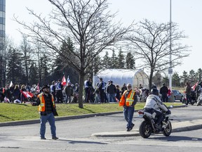A man waves a Canadian flag as a Rolling Thunder convoy members arrives at St-Laurent Mall to gather before their route in the City of Ottawa Saturday Morning.