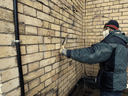 A church worker uses removes a swastika that was spray-painted on the outside wall of Metropolitan United Church in Toronto, March 8, 2022.