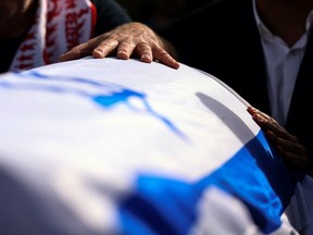 A mourner places his hands on the coffin of Tomer Morad who was killed during a Tel Aviv bar attack by a Palestinian gunman, at his funeral in Kfar Saba, Israel, April 10, 2022. REUTERS/Ronen Zvulun