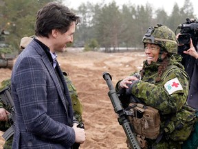 Canadian Prime Minister Justin Trudeau, left, talks with a Canadian soldier during his visit to Adazi Military base in Kadaga, Latvia, Tuesday, March. 8, 2022.