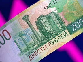 A Russian ruble banknote is seen in front of a descending stock chart in this illustration taken on March 1, 2022.