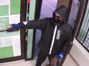 A suspect attempts to rob a Calgary cannabis store in a security image released by police in June 2021. Opaque window coverings are aiding criminals in a Calgary spree of pot shop robberies, writes Colby Cosh.