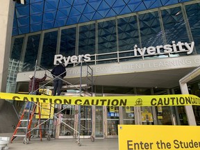 Workers replace a Ryerson University sign after the institution announced it was changing its name to Toronto Metropolitan University, on April 26, 2022.