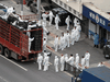 People wearing personal protective equipment transfer food supplies and necessities for local residents during a COVID-19 lockdown in Shanghai, April 5, 2022.