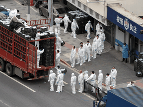 People wearing personal protective equipment transfer food supplies and necessities for local residents during a COVID-19 lockdown in Shanghai, April 5, 2022.