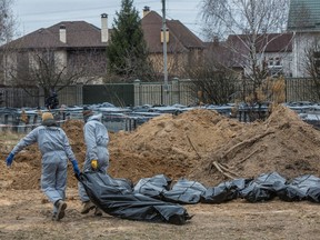 Forensic technicians carry pull the body of a civilian who Ukrainian officials say was killed during Russia’s invasion, then buried and exhumed from a mass grave in the town of Bucha, outside Kyiv, Ukraine April 13, 2022.