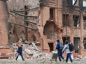 Mariupol residents walk past a building destroyed during the Ukraine-Russia war, on April 3, 2022.