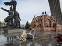 Menschen fotografieren am 26. April 2022 in Kiew ein sowjetisches Denkmal für eine Freundschaft zwischen ukrainischen und russischen Nationen, das abgerissen wird. 