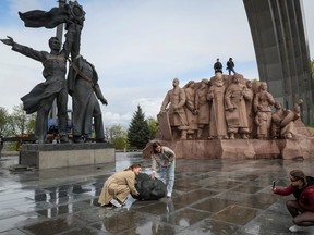 People take pictures of a Soviet monument to a friendship between Ukrainian and Russian nations as it is demolished, in Kyiv on April 26, 2022.