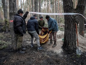 Residents carry the body of civilian woman identified as Yaroslava from a grave. According to residents, Yaraslova was killed by Russian soldiers in the village of Motyzhyn, in the Kyiv region, Ukraine, April 4, 2022.