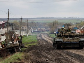 A Ukrainian tank drives next to a destroyed Russian vehicle, marked with the "Z" symbol, in the village of Husarivka on April 14.