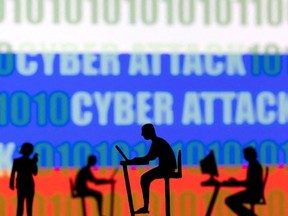 Figurines with computers and smartphones are seen in front of the words "Cyber Attack", binary codes and the Russian flag, in this illustration taken February 15, 2022. REUTERS/Dado Ruvic/Illustration/File Photo