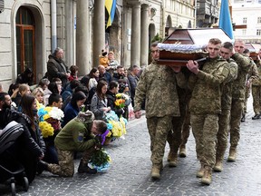 Ukrainian servicemen carry coffins with the bodies of three Ukrainian soldiers killed during Russia's invasion, during a ceremony in Lviv, western Ukraine, on April 28, 2022.