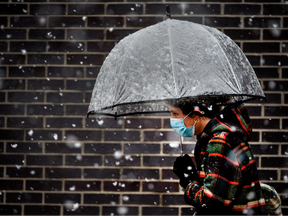 Ein Fußgänger geht am Montag, den 18. April 2022, durch einen Schneefall auf der Beverly Street in Toronto.