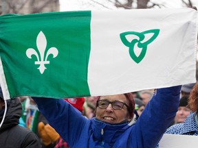 A woman holds up the Franco-Ontario flag in front of the Human Rights building during the Franco-Ontario Day of Action in Ottawa, Ontario on Dec. 1 2018.