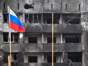 Eine russische Nationalflagge weht am 12. April an zerstörten Gebäuden in Mariupol vorbei.