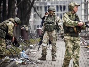 Russian soldiers walk along a street in Mariupol on April 12, 2022, as Russian troops intensify a campaign to take the strategic port city, part of an anticipated massive onslaught across eastern Ukraine, while Russia's President makes a defiant case for the war on Russia's neighbour.