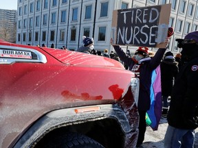 A person holds a sign as people take part in a counter-protest blocking a small convoy of truckers demonstrating against vaccine mandates, in the outskirts of Ottawa, on Feb. 13.