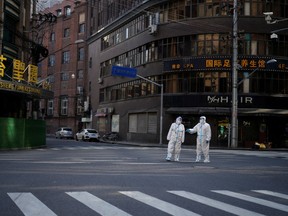 Workers in protective suits keep watch on a street during a lockdown in Shanghai, on April 16.