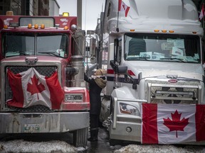 A woman greets a truck driver while vehicles line streets in Ottawa during the Freedom Convoy protest.